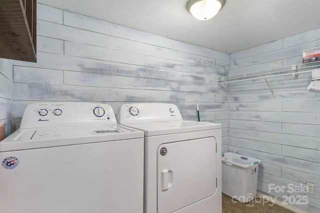 laundry room with washing machine and clothes dryer and wooden walls