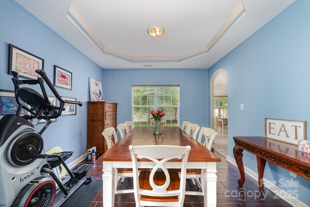 8927 Comstock Ct, Locust, NC 28097 - dining room featuring arched walkways, a tray ceiling, wood finished floors, and ornamental molding