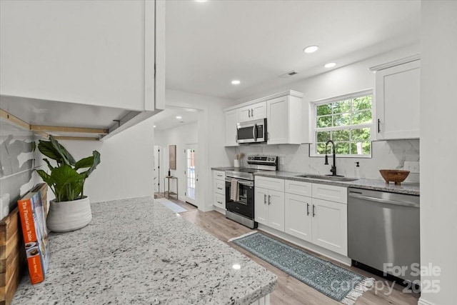 1015 4th St, Spencer, NC 28159 - kitchen featuring stainless steel appliances, a sink, light wood finished floors, recessed lighting, and white cabinets
