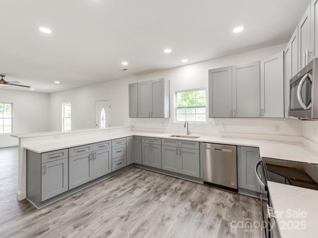 kitchen featuring stainless steel appliances, gray cabinets, a sink, healthy amount of natural light, and recessed lighting