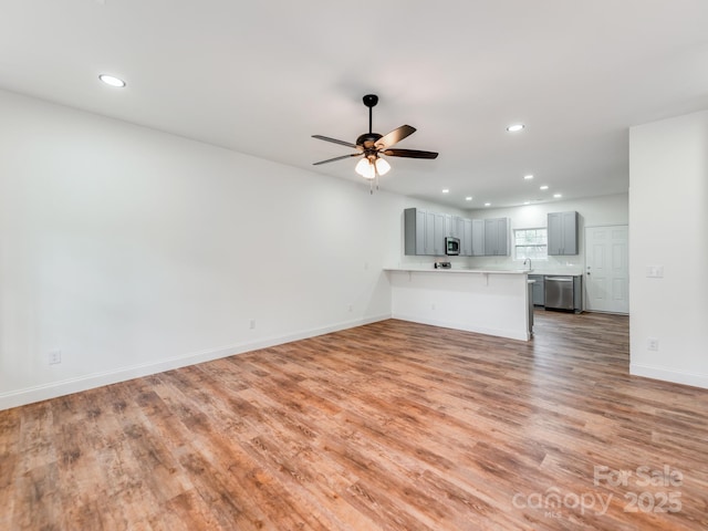 unfurnished living room featuring recessed lighting, light wood-type flooring, a ceiling fan, and baseboards