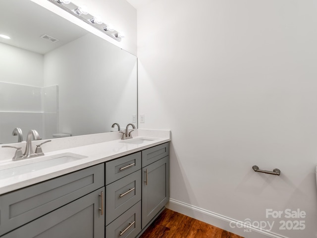 full bath with wood finished floors, double vanity, and baseboards