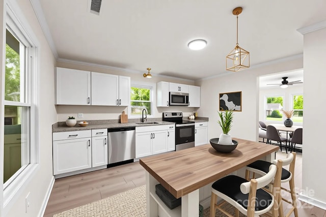 1155 Cedar Grove Ln, Rock Hill, SC 29732 - kitchen with appliances with stainless steel finishes, white cabinetry, ornamental molding, hanging light fixtures, and a breakfast bar area