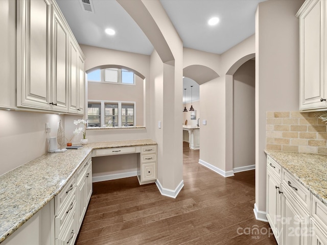 1190 Arges River Dr, Fort Mill, SC 29715 - kitchen featuring dark wood-style flooring, decorative backsplash, arched walkways, light stone countertops, and recessed lighting