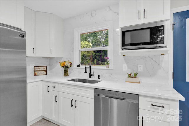 4108 Mellon Rd, Matthews, NC 28104 - kitchen with appliances with stainless steel finishes, a sink, light stone counters, white cabinets, and backsplash