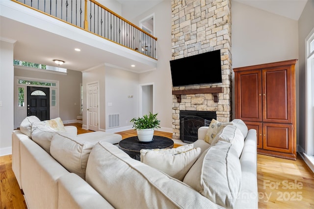 6409 Barkley Farm Rd, Huntersville, NC 28078 - living room featuring a towering ceiling, light wood-style floors, a stone fireplace, baseboards, and plenty of natural light