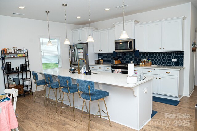 10100 Jack Nicklaus Dr, Lancaster, SC 29720 - kitchen featuring a sink, appliances with stainless steel finishes, a breakfast bar area, a center island with sink, and white cabinets