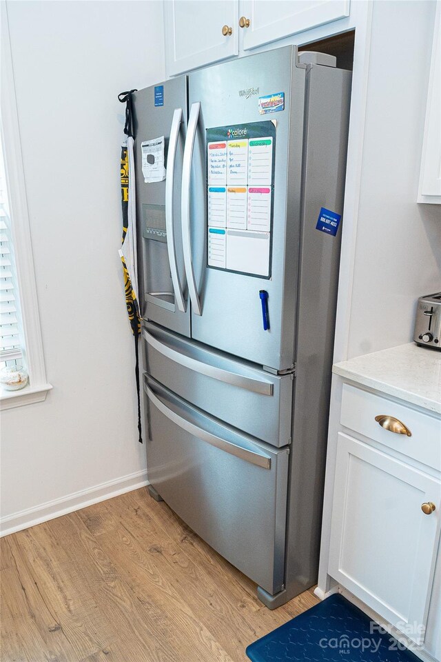 10100 Jack Nicklaus Dr, Lancaster, SC 29720 - detailed view of smart refrigerator, light wood-type flooring, white cabinetry, and baseboards