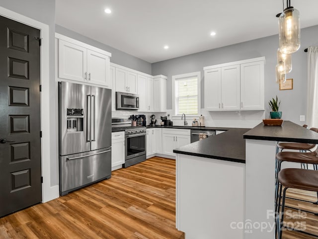 20 Phillip Ln, Arden, NC 28704 - kitchen with high end appliances, a peninsula, light wood-style flooring, dark countertops, and a breakfast bar area