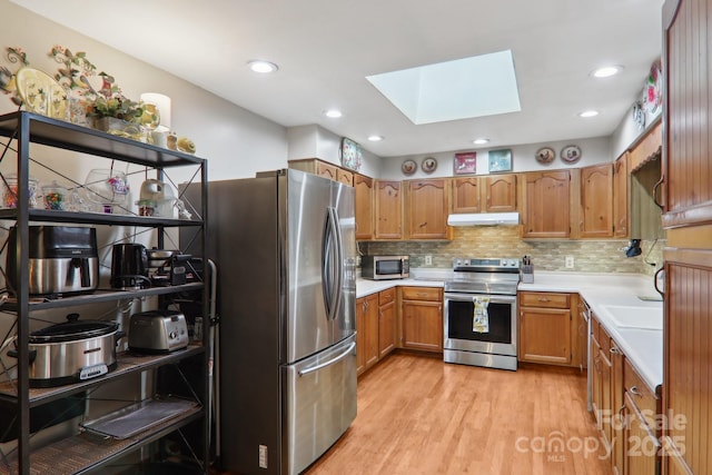 457 Shady Ridge Rd, Waynesville, NC 28785 - kitchen featuring appliances with stainless steel finishes, under cabinet range hood, a skylight, light countertops, and light wood-style flooring