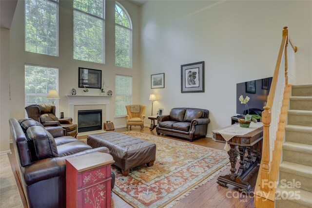 12125 Mountainside Ln, Charlotte, NC 28278 - living room with a high ceiling, stairs, a glass covered fireplace, baseboards, and wood finished floors