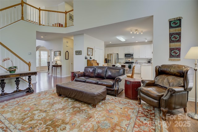 12125 Mountainside Ln, Charlotte, NC 28278 - living room featuring stairway, light wood-type flooring, arched walkways, and baseboards