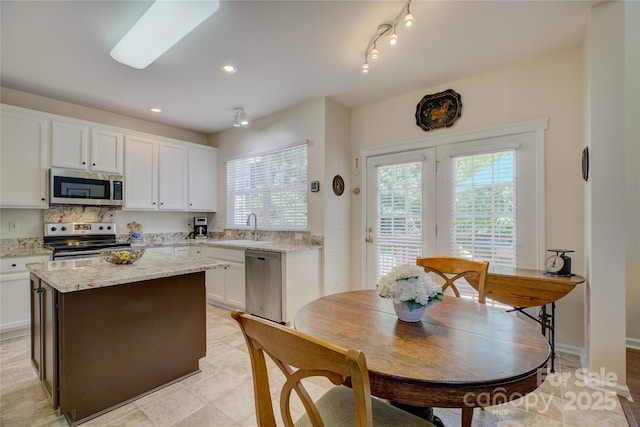 12125 Mountainside Ln, Charlotte, NC 28278 - kitchen with stainless steel appliances, a sink, white cabinets, a kitchen island, and light stone counters