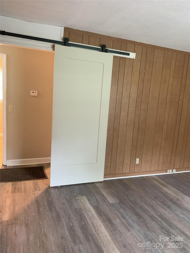 304 W Miller St, Jefferson, SC 29718 - empty room with wood finished floors, a barn door, wood walls, and baseboards