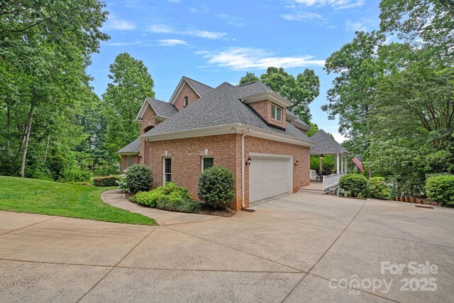 166 Pinnacle Shores Dr, Mooresville, NC 28117 - view of home's exterior featuring roof with shingles, brick siding, driveway, a yard, and an attached garage