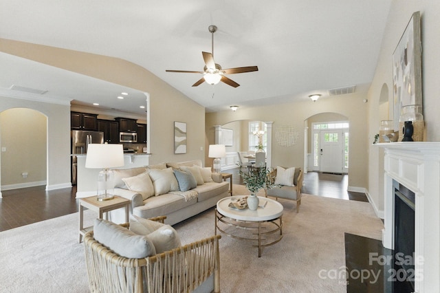 living room featuring arched walkways, ceiling fan, vaulted ceiling, and baseboards