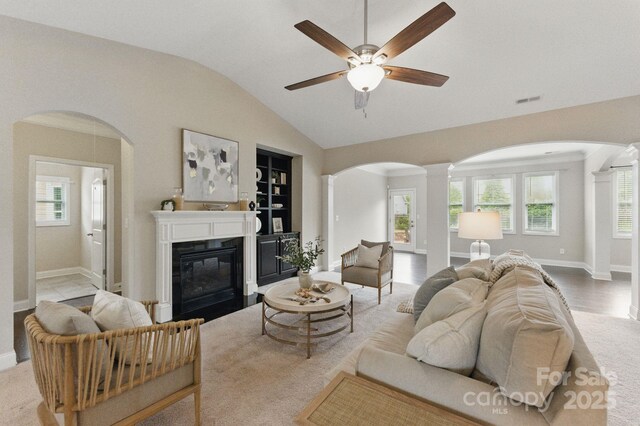 living room featuring arched walkways, vaulted ceiling, ornate columns, carpet, and ceiling fan