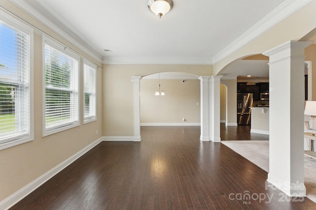 unfurnished room with decorative columns, arched walkways, dark wood-style flooring, ornamental molding, and baseboards