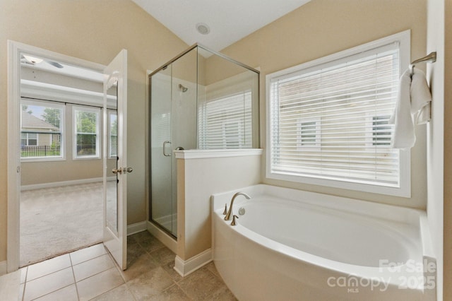bathroom with a garden tub, a shower stall, tile patterned flooring, and baseboards