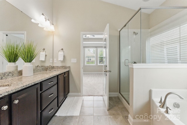 bathroom featuring a shower stall, double vanity, a garden tub, and baseboards