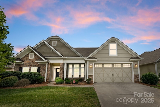 view of front facade with concrete driveway, stone siding, a yard, and an attached garage