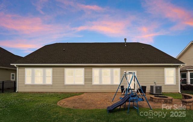 back of house featuring a fire pit, central air condition unit, a patio area, a lawn, and a shingled roof