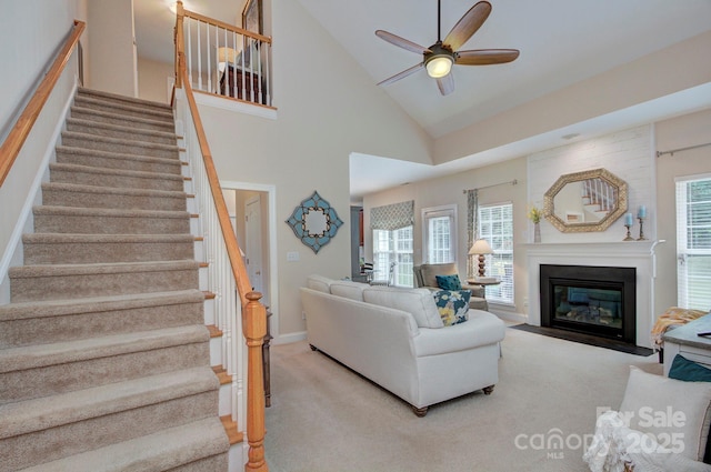 5748 Timbertop Ln, Charlotte, NC 28215 - carpeted living area with stairway, a ceiling fan, a fireplace with flush hearth, baseboards, and high vaulted ceiling