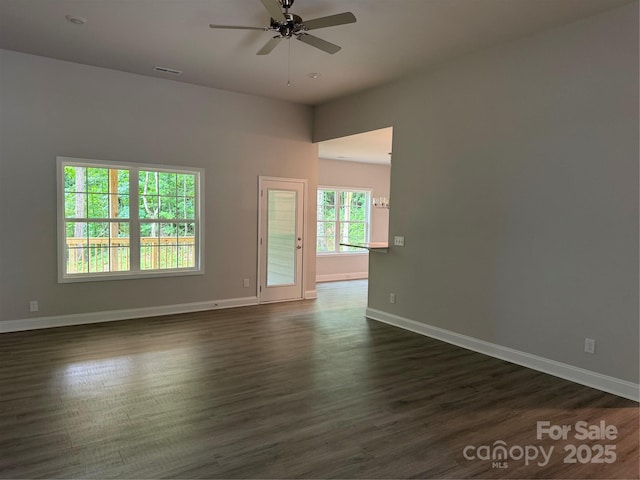 empty room featuring ceiling fan, dark wood-style floors, and baseboards