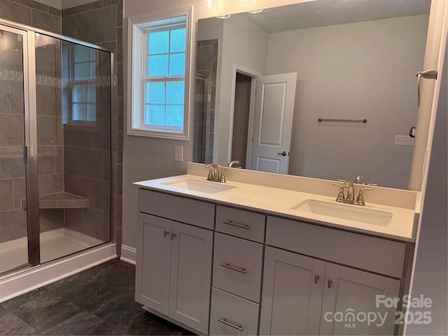 bathroom featuring a shower stall, double vanity, and baseboards