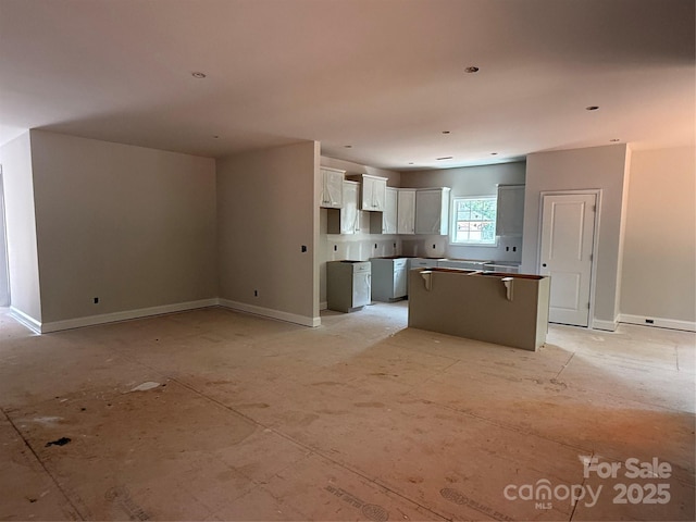 kitchen featuring a center island, white cabinets, and baseboards