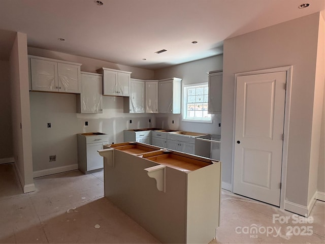 kitchen with a center island, baseboards, and white cabinets