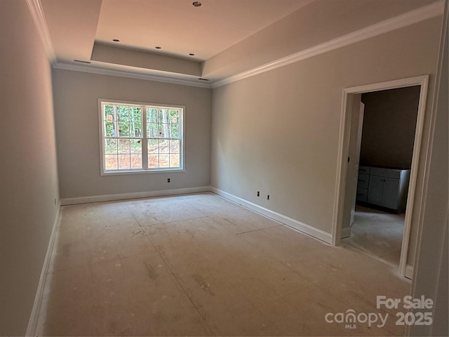 spare room featuring crown molding, a raised ceiling, and baseboards