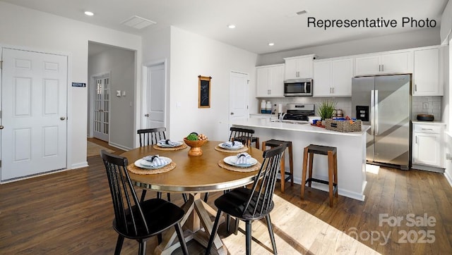 dining room featuring dark wood-type flooring, recessed lighting, and baseboards