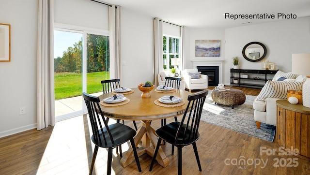 dining room with a glass covered fireplace, wood finished floors, and baseboards