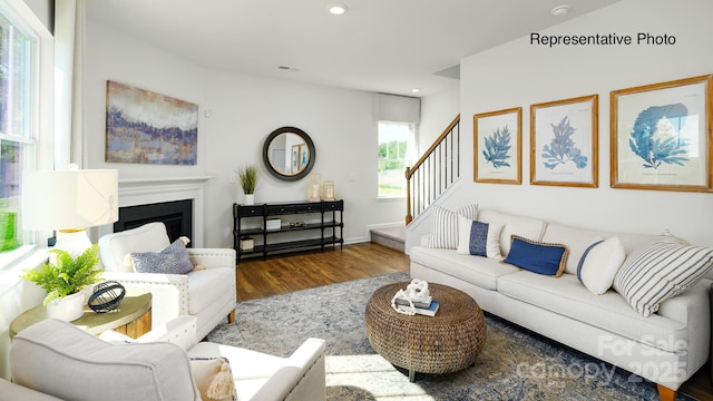 living room featuring wood finished floors, stairway, recessed lighting, and a fireplace