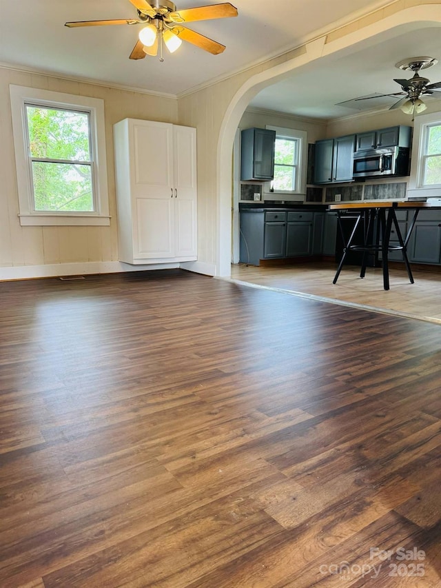 kitchen featuring stainless steel microwave, a ceiling fan, healthy amount of natural light, arched walkways, and crown molding