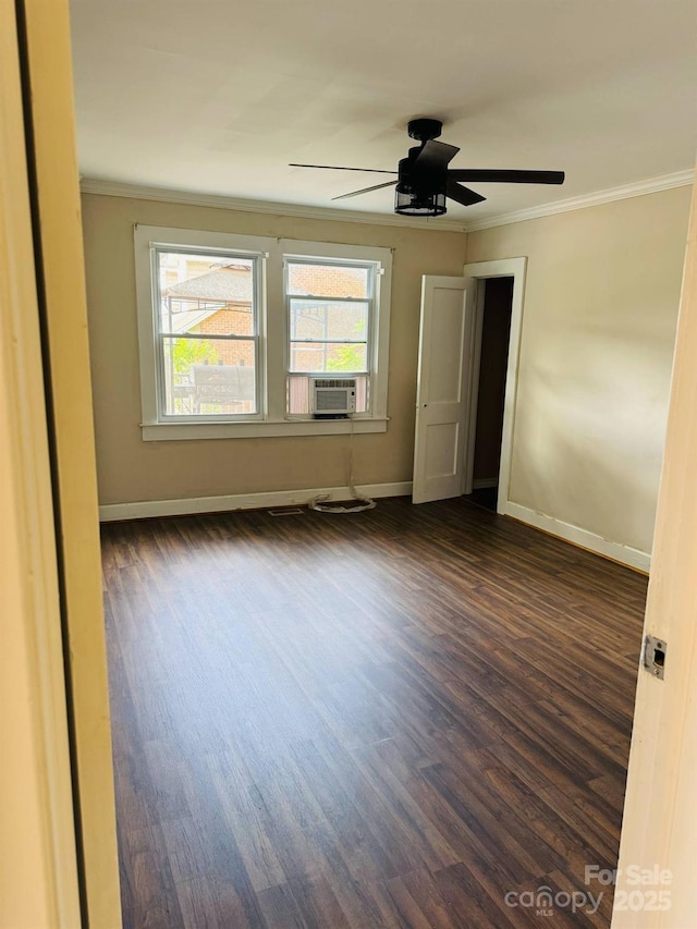 spare room featuring ornamental molding, dark wood-style floors, baseboards, ceiling fan, and cooling unit