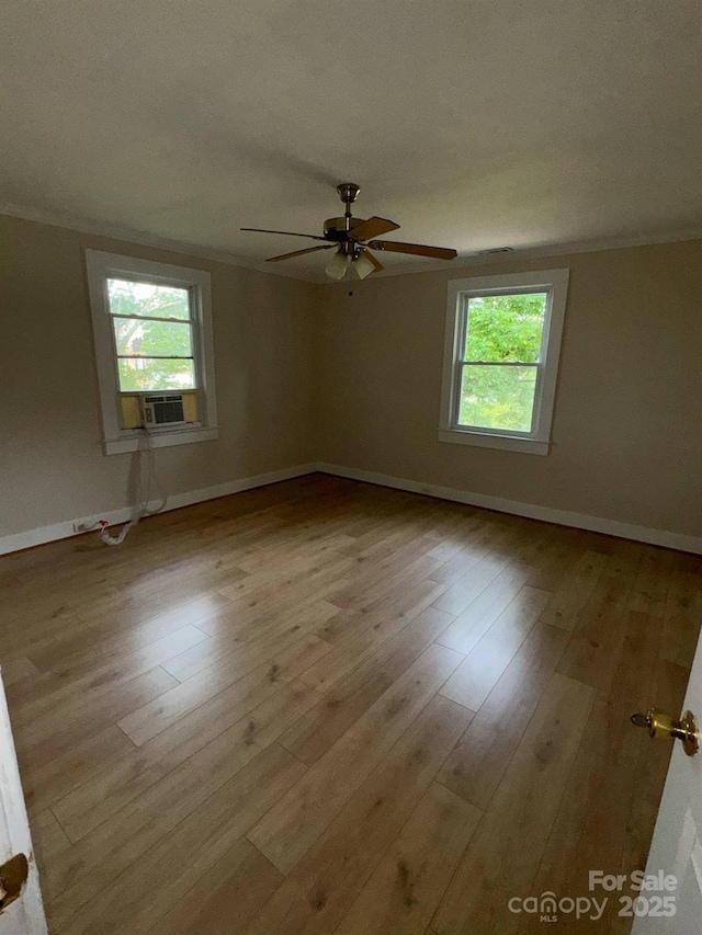 spare room with healthy amount of natural light, ornamental molding, ceiling fan, and wood finished floors