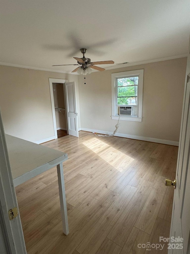 spare room with baseboards, crown molding, ceiling fan, wood finished floors, and cooling unit
