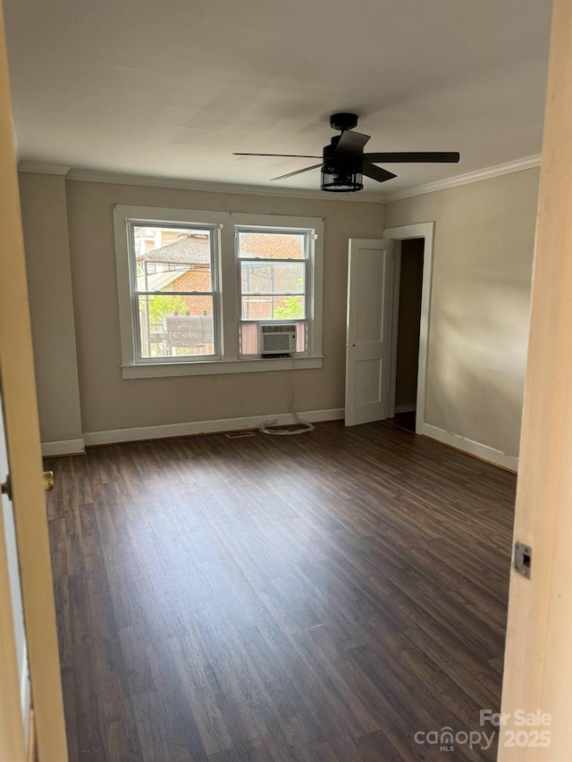 empty room featuring ornamental molding, dark wood finished floors, baseboards, cooling unit, and ceiling fan