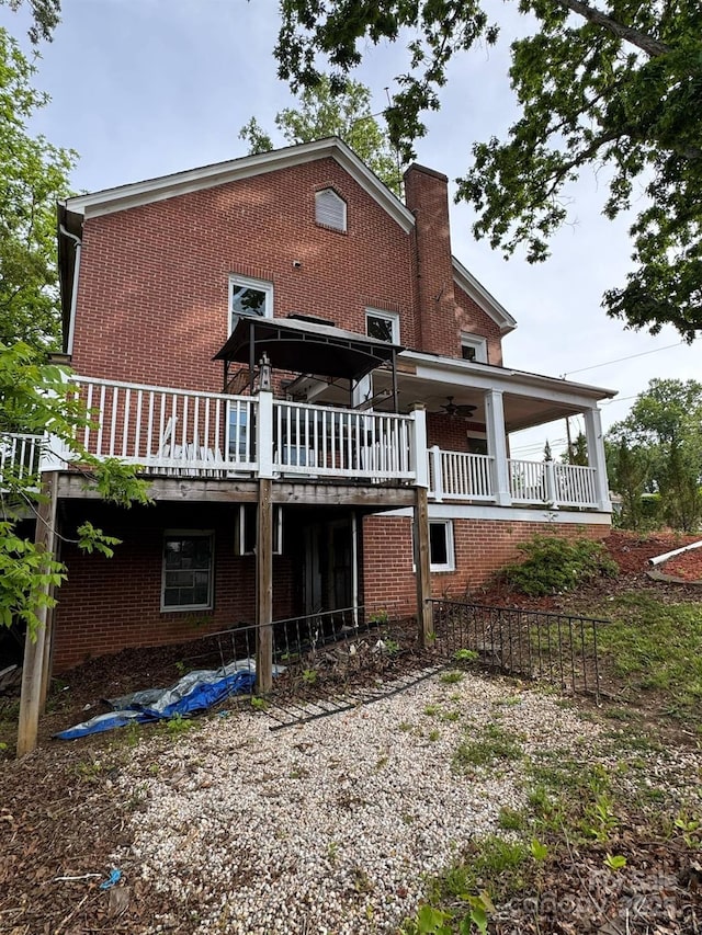 back of house featuring a ceiling fan, brick siding, a wooden deck, and a chimney