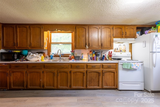 100 Lanier St, Mount Holly, NC 28120 - kitchen with white appliances, under cabinet range hood, brown cabinets, a sink, and a textured ceiling