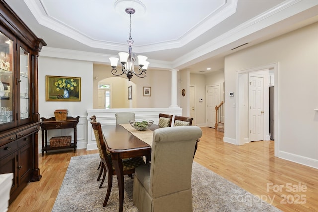 3128 Ethereal Ln, Charlotte, NC 28226 - dining space with a chandelier, a raised ceiling, crown molding, light wood-style flooring, and ornate columns