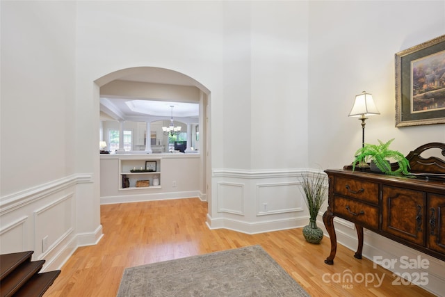 3128 Ethereal Ln, Charlotte, NC 28226 - hall featuring arched walkways, light wood-style floors, a chandelier, and a wainscoted wall