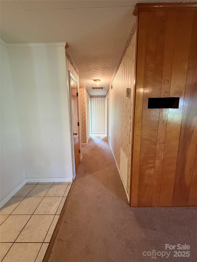 corridor featuring light carpet, baseboards, and light tile patterned flooring