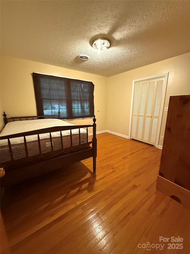bedroom featuring wood finished floors, a textured ceiling, and baseboards