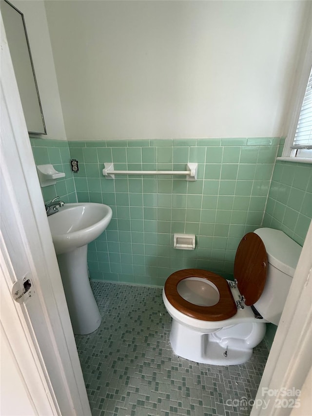 bathroom with tile walls, toilet, tile patterned flooring, and a wainscoted wall