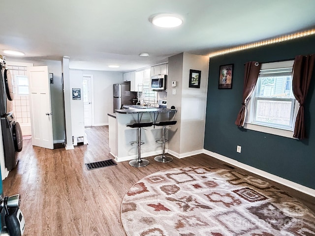 116 N Blue Ridge Ave, Hendersonville, NC 28792 - kitchen featuring stacked washer and clothes dryer, appliances with stainless steel finishes, a peninsula, a kitchen breakfast bar, and white cabinetry