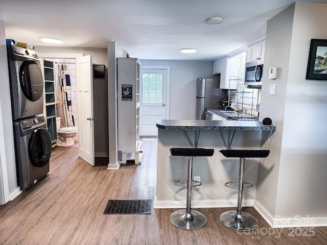 116 N Blue Ridge Ave, Hendersonville, NC 28792 - kitchen featuring estacked washer and dryer, appliances with stainless steel finishes, dark countertops, a peninsula, and a breakfast bar