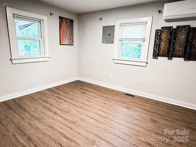 116 N Blue Ridge Ave, Hendersonville, NC 28792 - spare room featuring a wall mounted air conditioner, electric panel, plenty of natural light, and wood finished floors